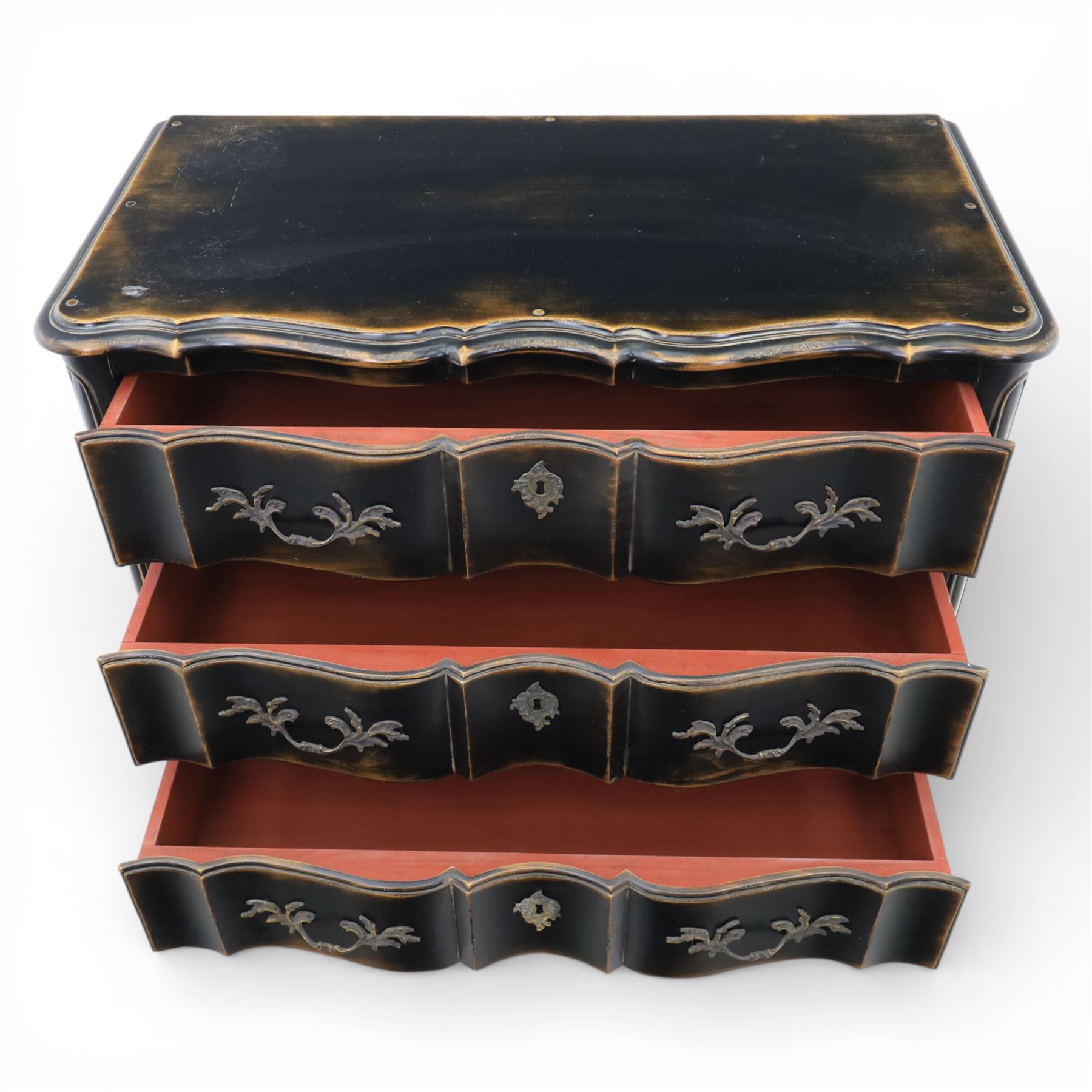 French style black lacquered chest of drawers, the serpentine front fitted with three graduated drawers mounted with scrolling foliate metal handles and key plates, shaped apron and scrolled cabriole legs