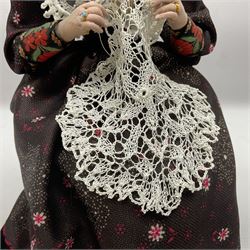 Anna Meszaros Hungary - hand made needlework figurine 'Old Lady' seated on a stool wearing a lace trimmed black/white/red floral full length dress and hat, working on a piece of lace H30cm  Auctioneer's Note: Anna Meszaros came to England from her native Hungary in 1959 to marry an English businessman she met while demonstrating her art at the 1958 Brussels Exhibition. Shortly before she left for England she was awarded the title of Folk Artist Master by the Hungarian Government. Anna was a gifted painter of mainly portraits and sculptress before starting to make her figurines which are completely hand made and unique, each with a character and expression of its own. The hands, feet and face are sculptured by layering the material and pulling the features into place with needle and thread. She died in Hull in 1998.