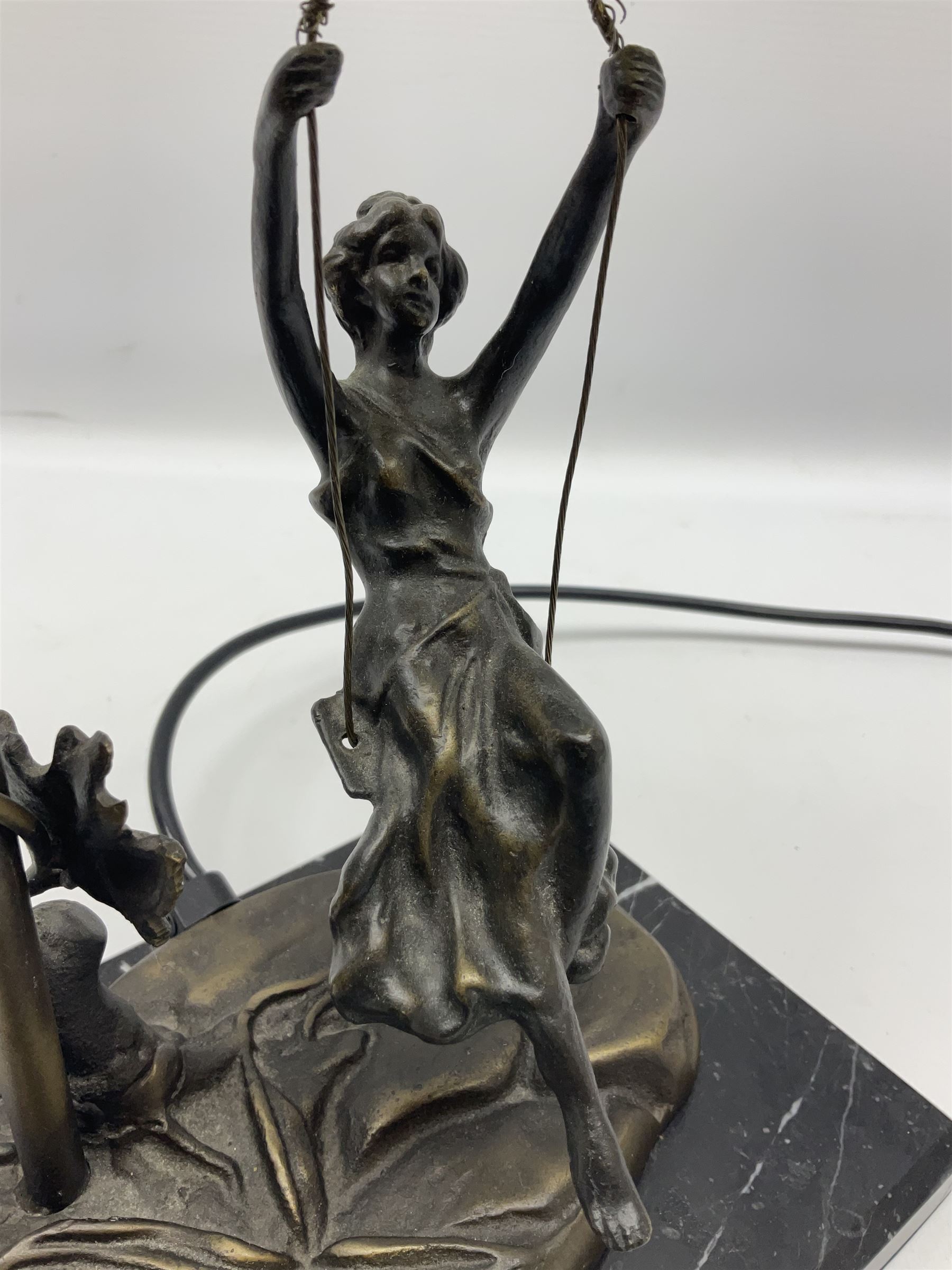 Art Nouveau style lamp in the form of a woman on a swing, with a green mottled shade, upon a marble base H52cm