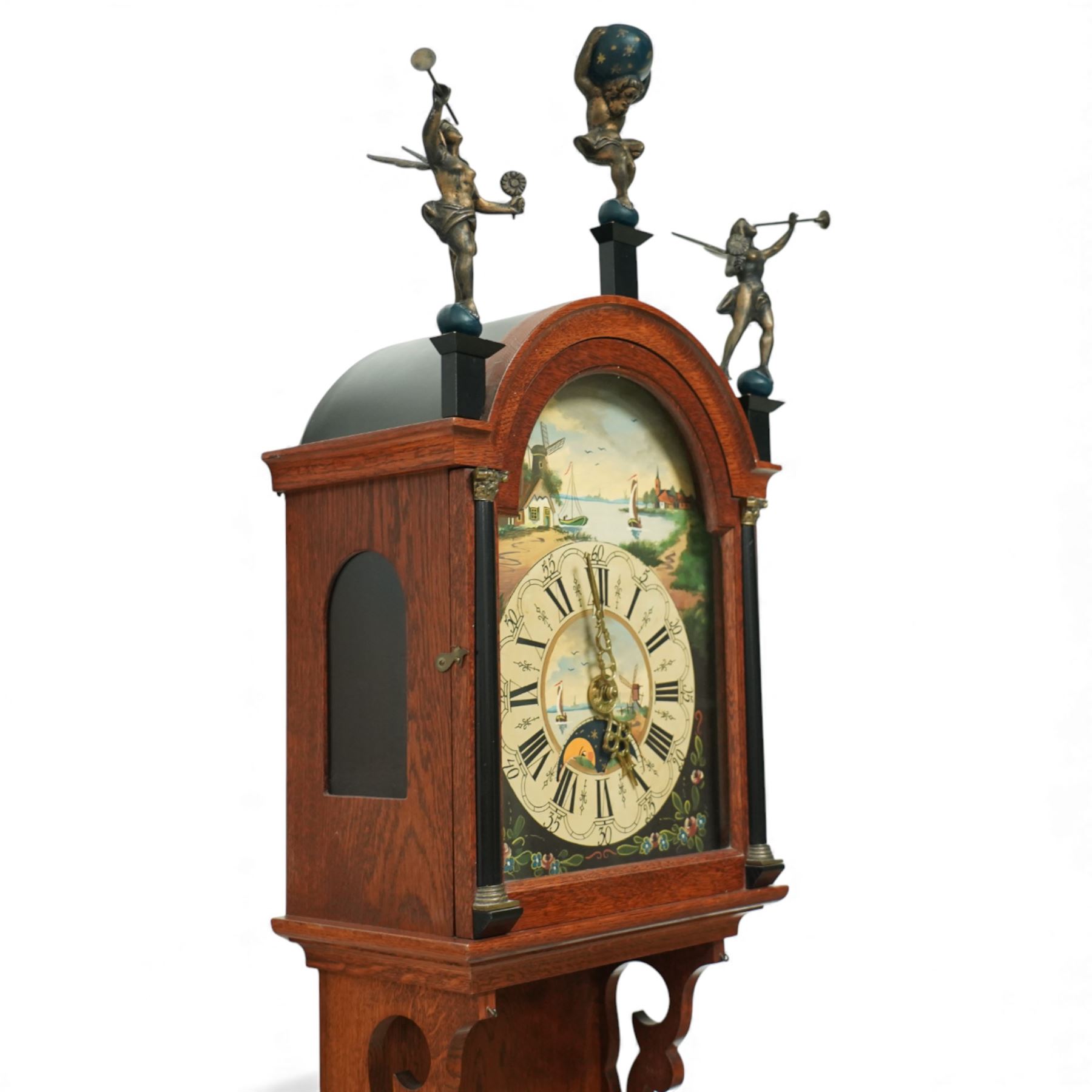 Dutch-mid 20th century Warmink WUBA wall clock, with a full length backboard and break arch hood with ebonised pilasters and three cast figures representing two trumpeting angels and Atlas to the pediment, with a fully painted break arch dial with a working axe moon dial and calendar aperture, chapter with Dutch minute arcading, Roman numerals and five minute Arabic's, three train chain driven countwheel striking movement with alarm and hours sounding on a bell. With three brass weights, brass chains and pendulum.