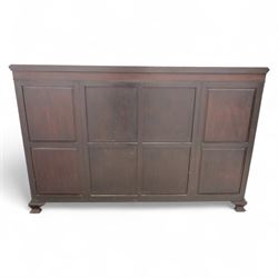 Edwardian mahogany serpentine breakfront display cabinet in the neoclassical style, the rectangular top above a carved frieze with roundels, foliage, and ribbon tied swags with central bow-fronted astragal glazed doors enclosing shelves, flanked by panelled doors, raised on bracket feet 