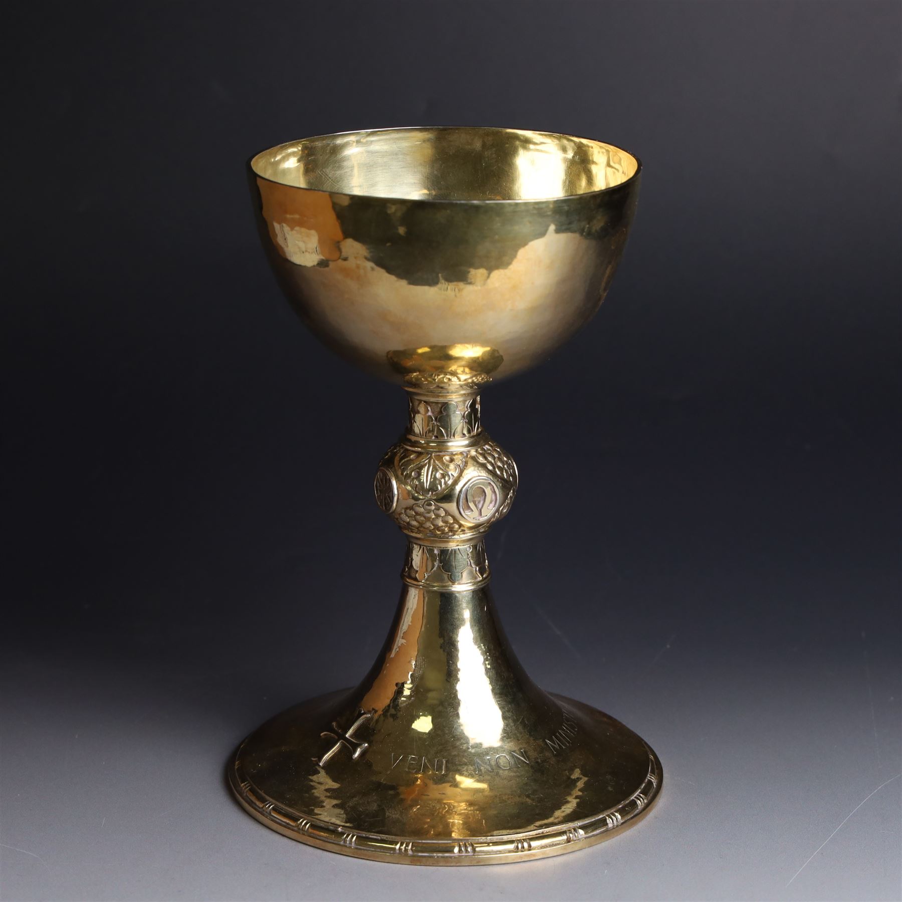 Mid 20th century silver-gilt chalice, the goblet with hammered finish upon knopped stem, the knop embossed with symbols and foliate decoration, engraved to base ' veni non ministrari sed ministrare' and with presentation engraving to underside, hallmarked Guild of Handicraft, London 1957, H17cm
