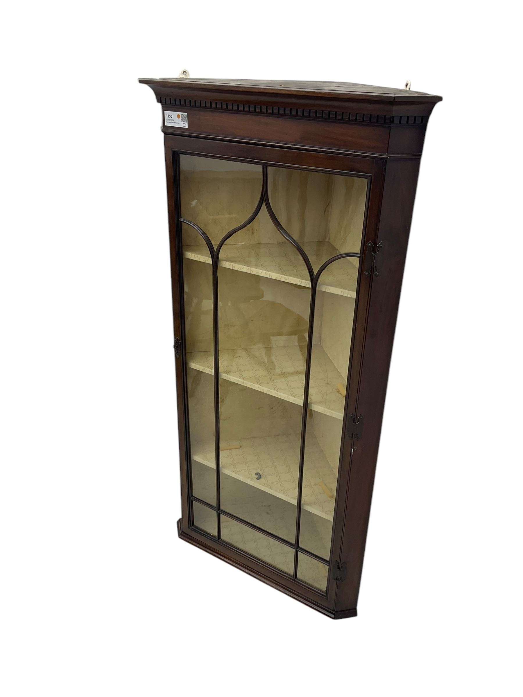 Early 20th century Georgian design mahogany wall-mounted corner display cabinet, projecting cornice with dentil frieze over astragal glazed door enclosing three fabric-lined shelves