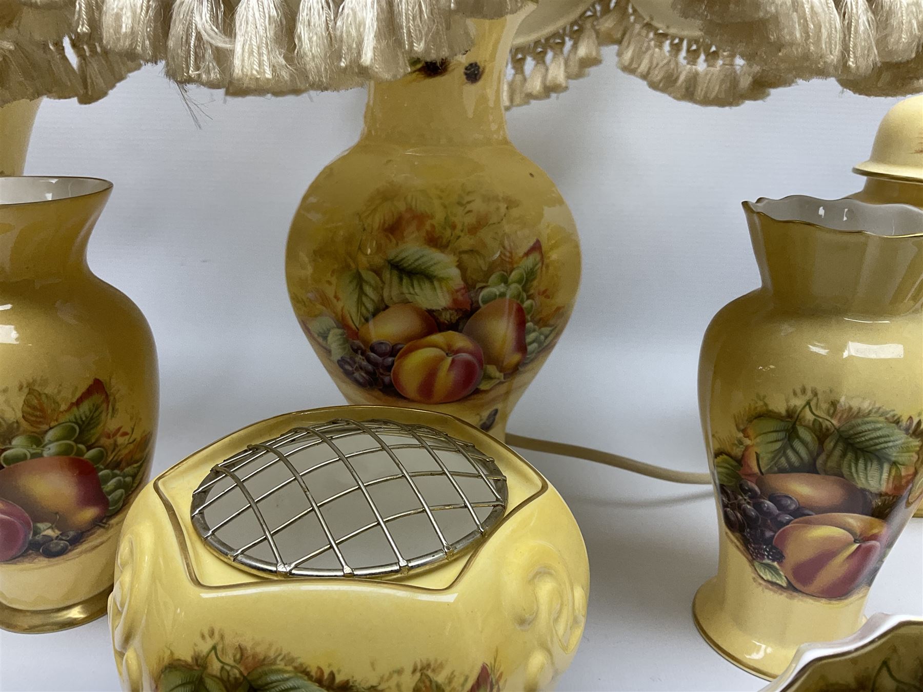 Collection of Aynsley Orchard Gold pattern wares, comprising lamp base, three jars and covers, six vases or various size and form, large jug, lidded dish, pair of cruets, pair of candlesticks, mug, two pin dishes, lobed dish, tea cup, saucer, size plate, and cake plate, and two further cups and saucers, each cup decorated with central Orchard Gold reserve to the interior against a mottled pink or green ground. 