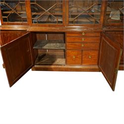 Fine Regency mahogany breakfront library bookcase, the stepped and moulded cornice over four astragal glazed doors enclosing adjustable shelves, the projecting central lower section with a pair of panelled doors enclosing three graduated drawers with brass inset handles above two deep zinc-lined cellarette compartments, flanked by panelled cupboard doors enclosing shelves, the figured mahogany fronts with ebony line inlay, on moulded plinth bases