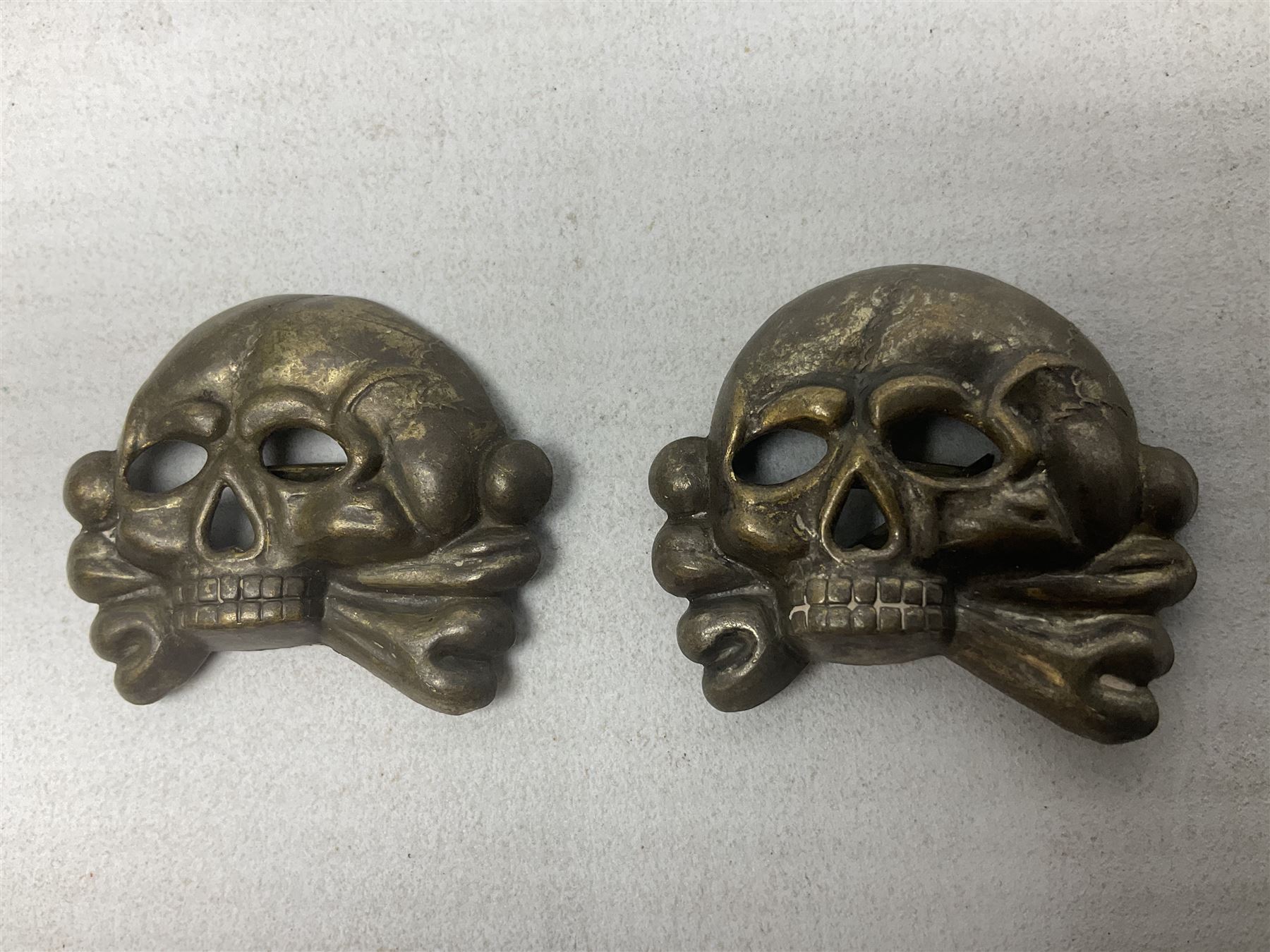 Two WW2 German 'SS' visor cap skull badges and another later; and visor cap eagle insignia (4)