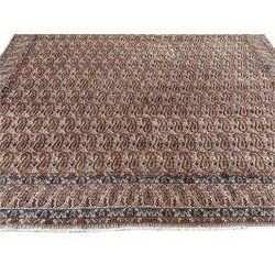 Persian Kirman carpet, the ivory ground field and border decorated with repeating Boteh motifs, interspaced with all-over floral design, blue ground border guards, the top border with signature panel