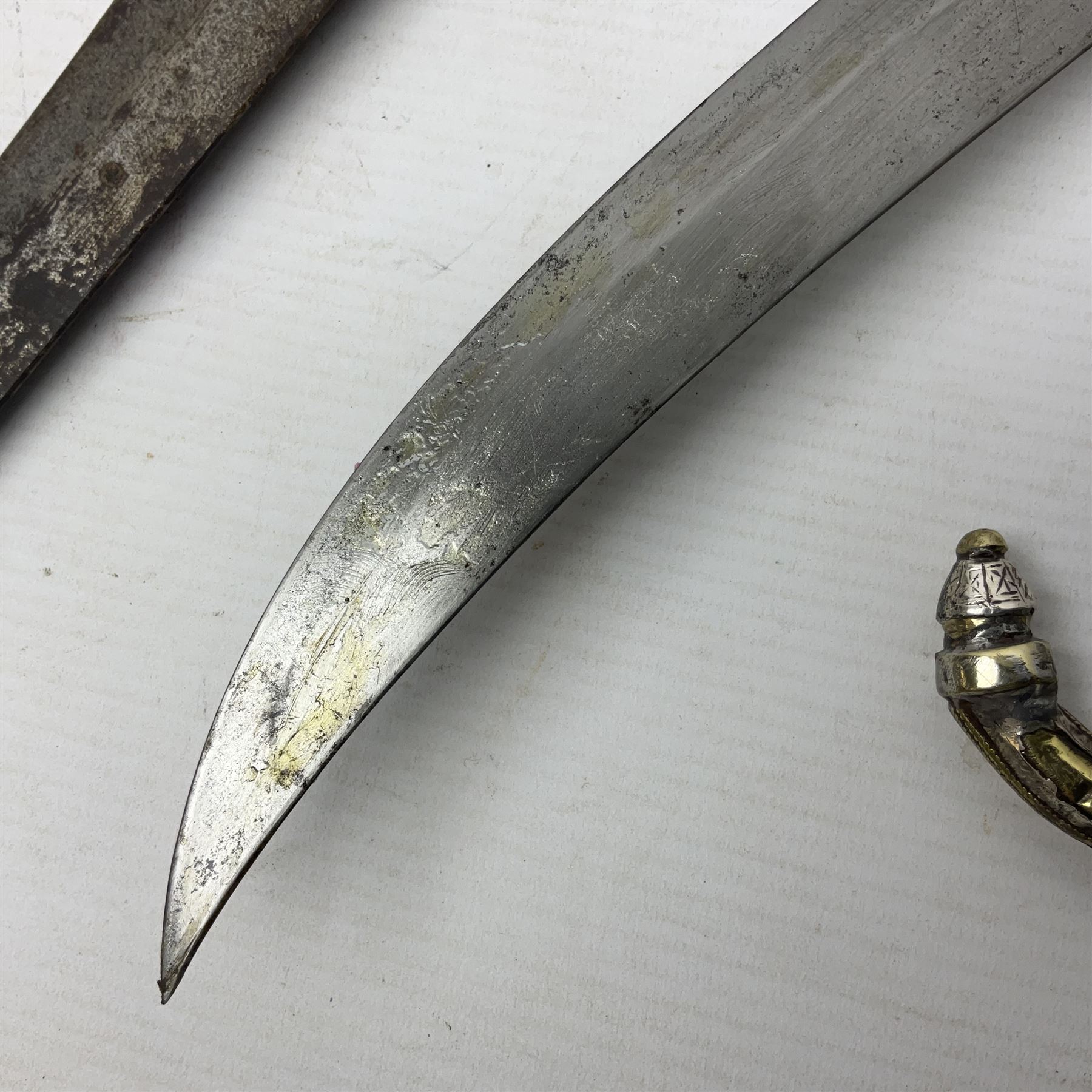 Moroccan jambiya dagger with 24.5cm plain curved blade stamped LONDON to the ricasso area, the hilt and scabbard overlaid with plain sheet brass to the back and ornate silver coloured metal to the front; waisted grip and arched pommel; two pyramid mounts to the scabbard L41cm overall; large billhook with curving blade and stacked leather washer grip; and a reproduction halberd blade (3)