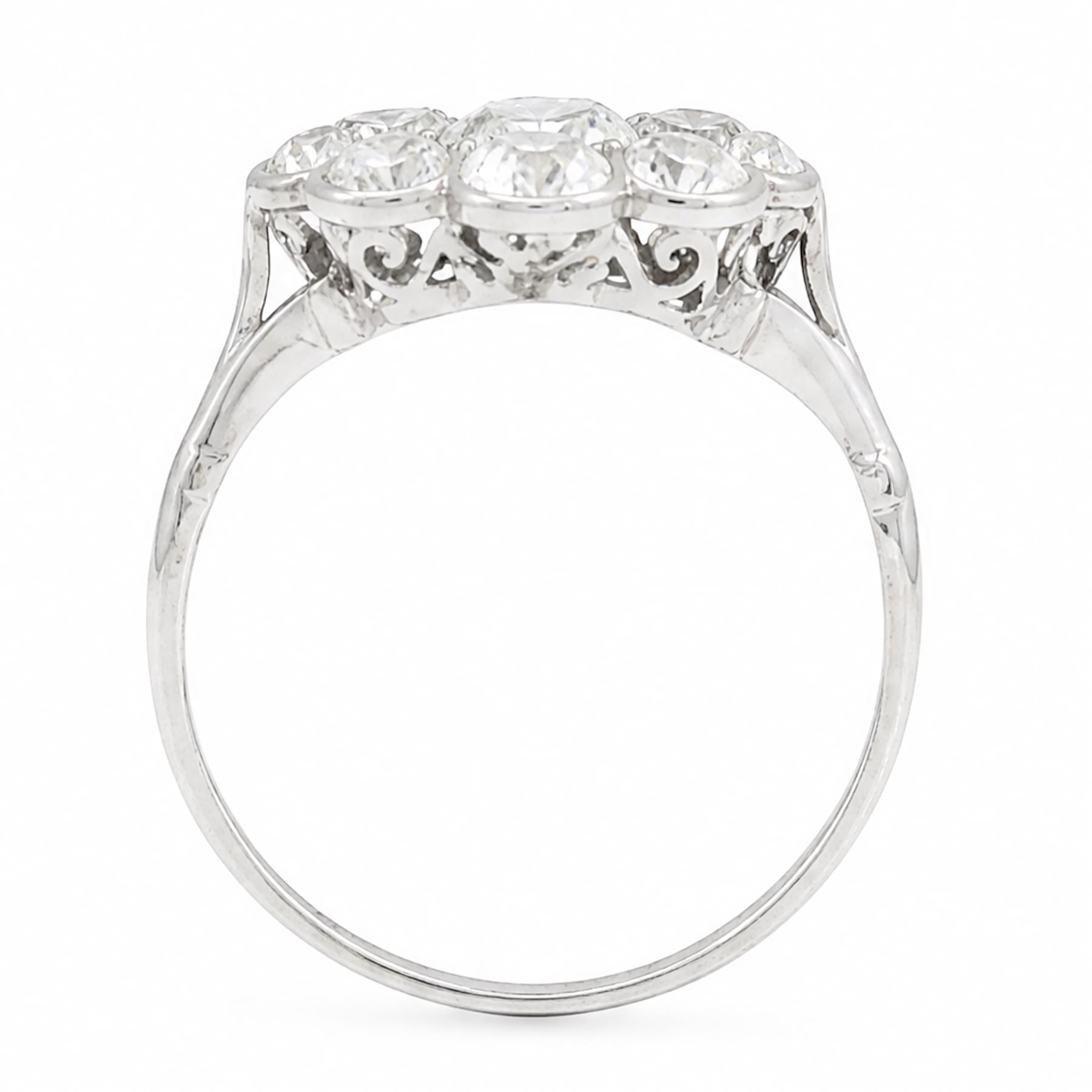 Early 20th century platinum diamond daisy flower head cluster ring, principal round cut diamond of approx 0.65 carat, surrounded by eight milgrain set old cut diamonds, within a pierced scroll design gallery, total diamond weight approx 2.15 carat