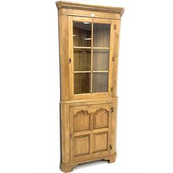 Oak corner cabinet, projecting cornice, dentil frieze, single glazed door enclosing two glass shelves above bottom unit, single fielded door enclosing fitted interior 