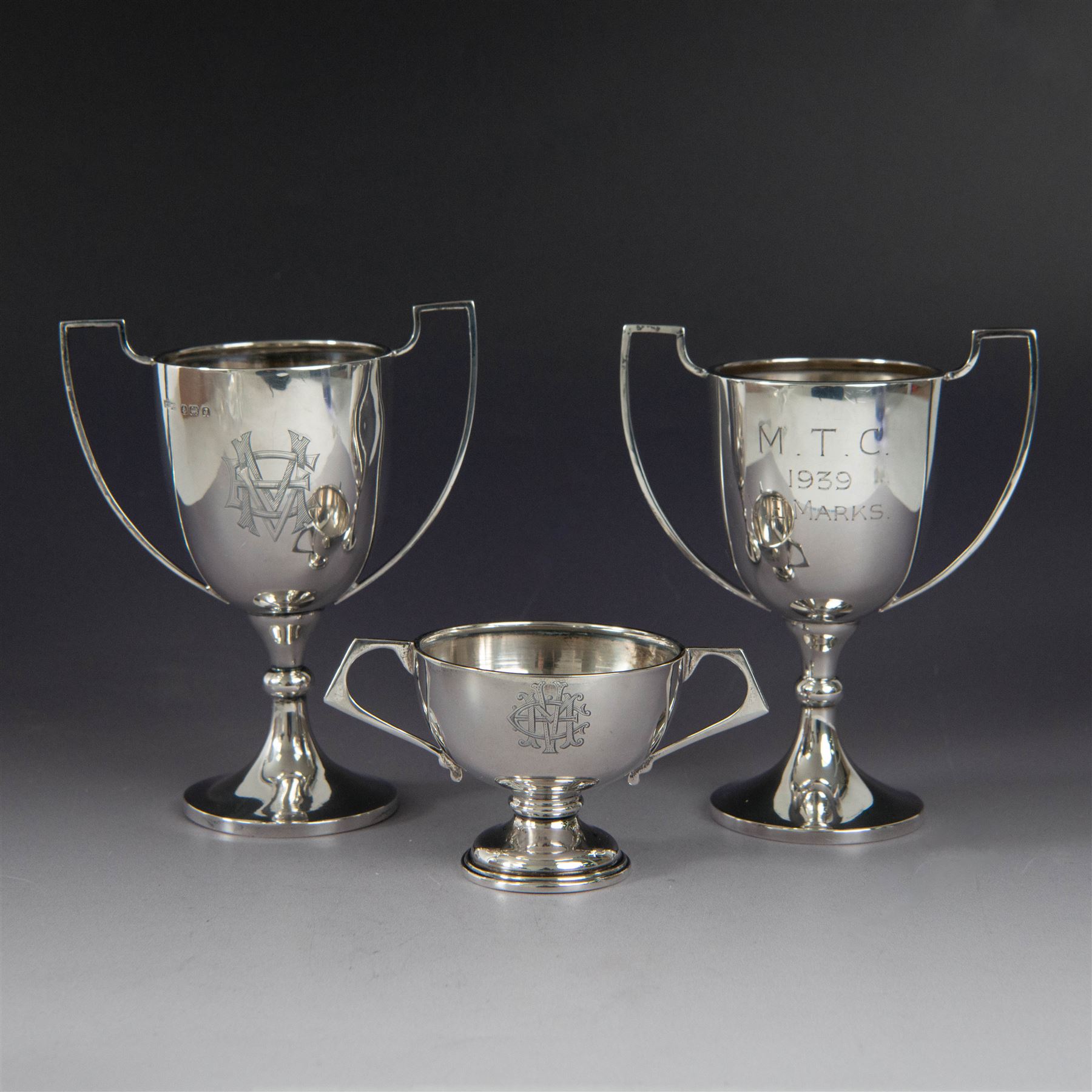 Pair of 1930s silver trophies, with angular handles and presentation engravings to body, hallmarked William Hair Haseler, Birmingham 1938, together with a similar smaller example, hallmarked Charles Boyton & Son Ltd,  London 1927, tallest H13cm
