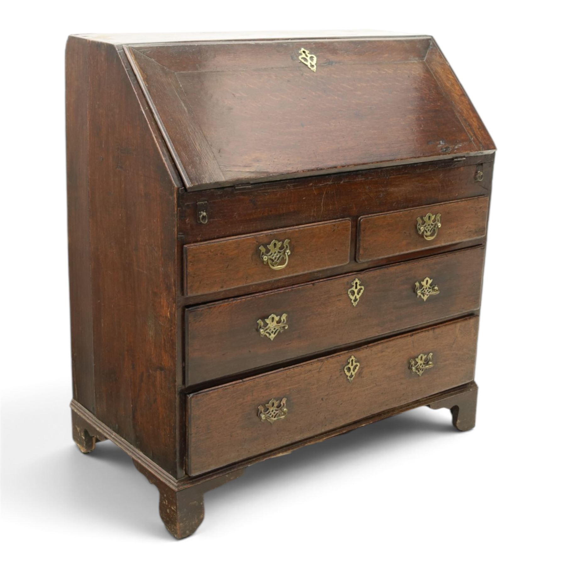 Georgian oak bureau, fall front with pierced brass escutcheon and handles, revealing a fitted interior, above two short over two long drawers, raised on bracket feet