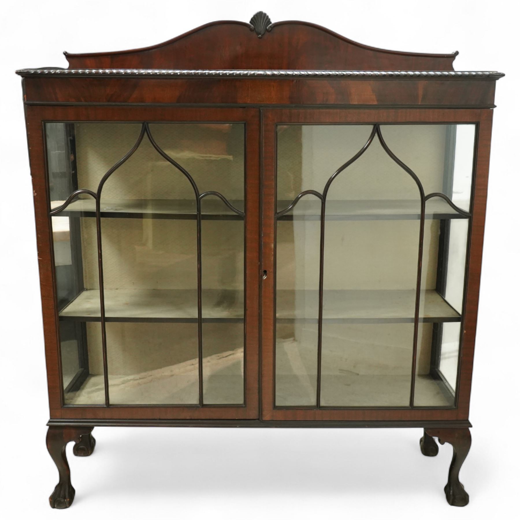 Early 20th century mahogany display cabinet, shaped pediment over a dentil moulded cornice, twin astragal glazed doors enclosing three shelves, raised on cabriole supports with pad feet
