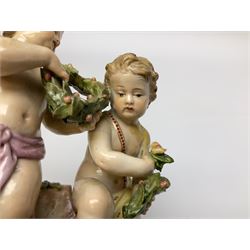 Meissen figure group modelled as two putto, one holding olive wreath and each kneeling upon a naturalistically modelled base also detailed with gilt C scrolls, with underglaze blue crossed swords mark beneath and impressed 2904, H12.5cm