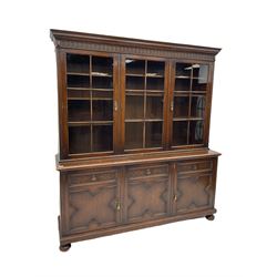 Waring and Gillow - oak bookcase on cupboard, projecting cornice over arcade frieze, guilloche upright decoration, the top section enclosed by three astragal glazed doors, the lower section enclosed by three geometric panelled doors with blind fretwork decoration, on turned feet