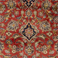 Persian Kashan carpet, the field in rich rust tone centred by an ivory and blue medallion with palmette extensions, surrounded by intricate foliate arabesques and stylised blooms, within triple floral borders incorporating palmettes and interlaced tendrils, woven in the region of Kashan