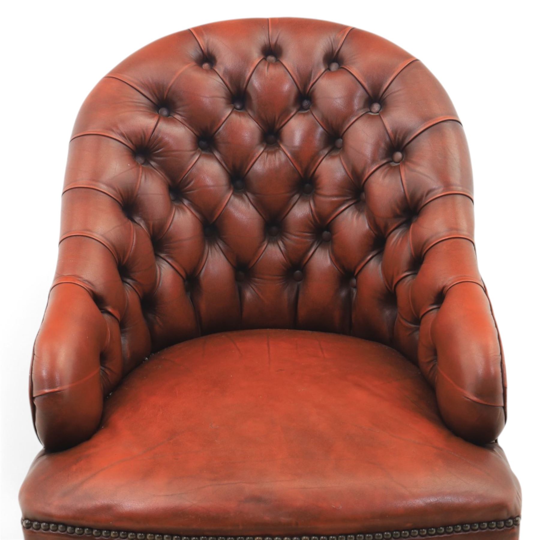 Victorian style oxblood leather armchair, deep button upholstered back and sides with rolled arms and brass studded borders, on turned front legs with brass and ceramic castors and splayed rear supports