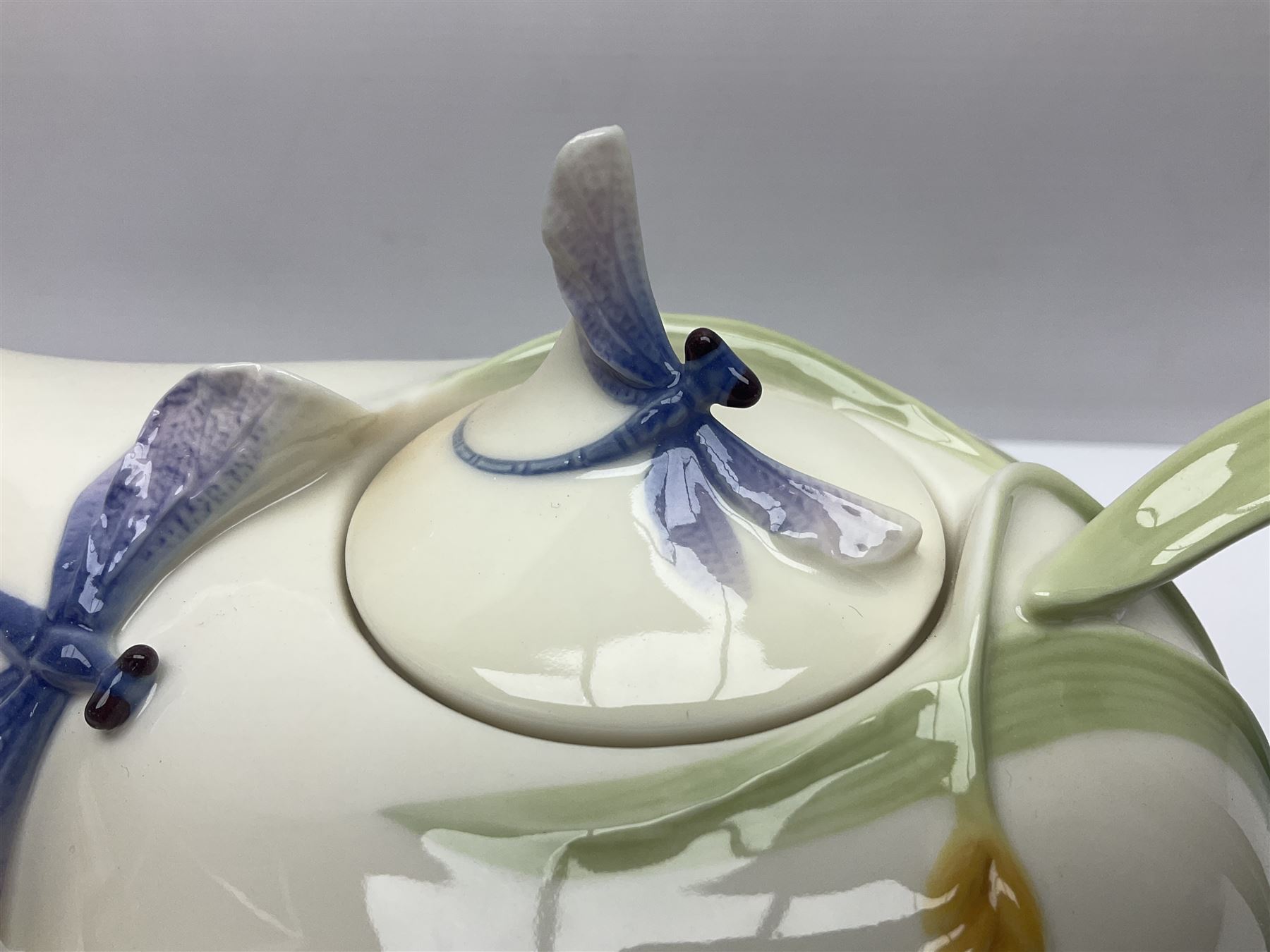 Franz Teapot decorated with dragonflies, together with a matching sucrier and cover and a cup and saucer in Iris pattern, all with printed mark beneath 