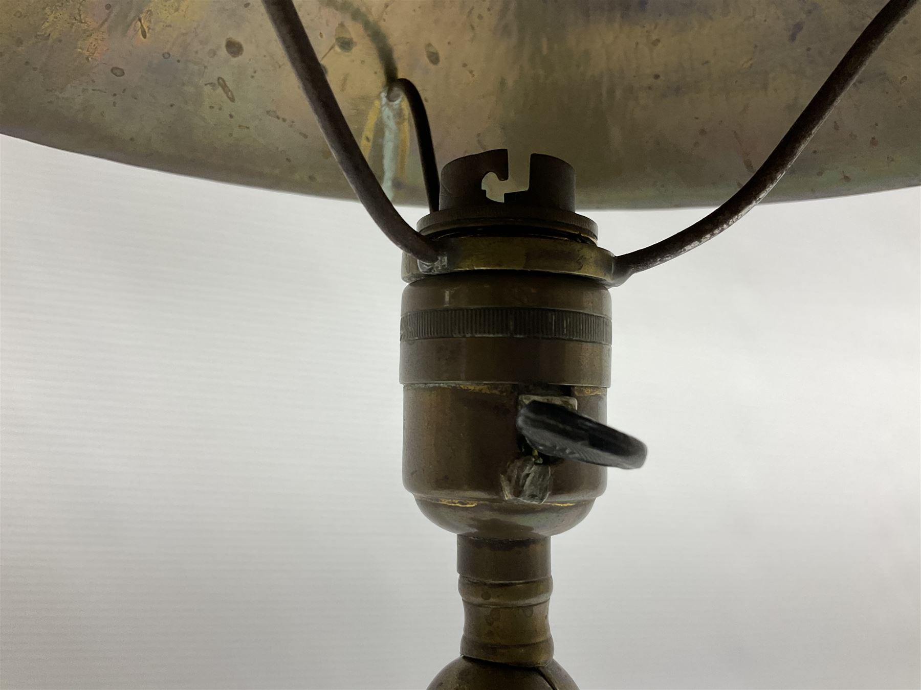 Arts & Crafts Jesson, Birkett & Co, brass table lamp or wall light, designed by Thomas Birkett, the tapering stem with adjustable ball pivot supporting a conical shade with tapering final with ball terminal, upon a circular domed base pierced for wall mounting, shade positioned upright overall H57cm

Often misattributed to Arthur Stansfield Dixon for Birmingham Guild of Handicraft, this particular lamp was designed by Thomas Birkett.
In the late 1890's Birkett worked as a metalwork at the Birmingham Guild, before later joining the Faulkner Bronze Company which went on to become Jesson, Birkett & Co in 1904. The lamp features in lighting catalogues from the firm under the model no E490.

