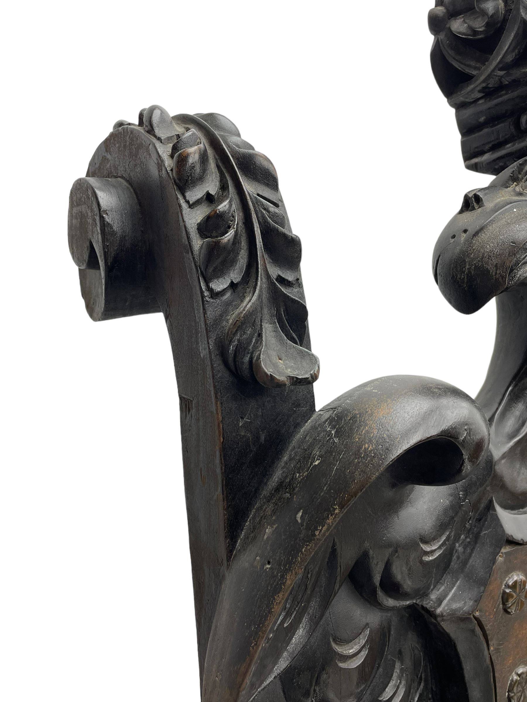 Grand mid-to-late 19th century heavily carved beech framed throne chair, the crown pediment carved with flower heads and cross finial, scroll and acanthus carved upright supports with twin perching griffin back enclosing etched leather work heraldic shield with castle and lion motifs over splayed feathers, flower head carved down sweeping arms with grotesque carved terminals, the seat rails carved with further flower heads on moulded supports with oversized ball and claw carved feet

Provenance: A very similar chair was used in the filming of Stanley Kubrick's 'Eyes Wide Shut' (1999)
