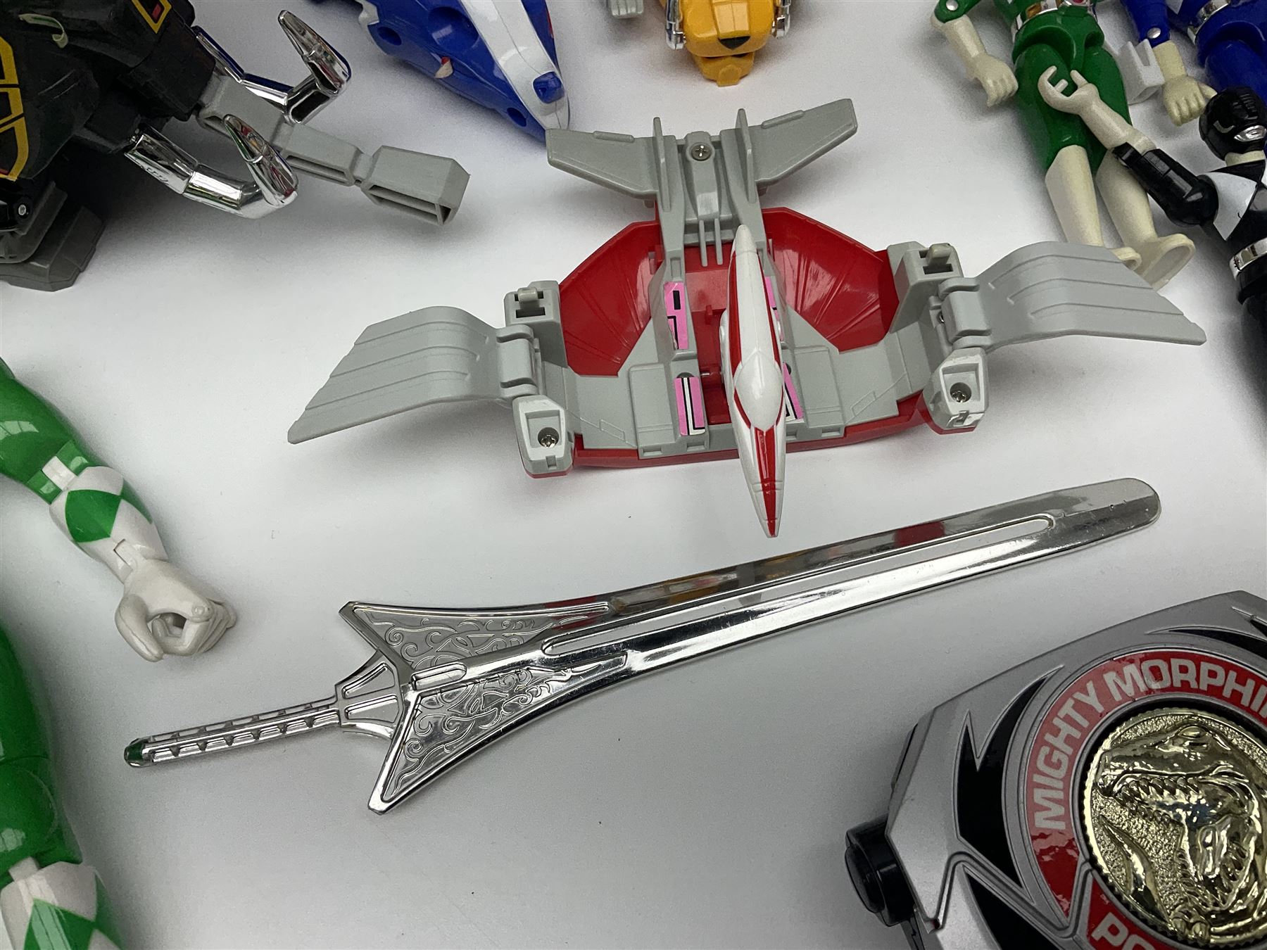 Collection of early 90s Mighty Morphin’ Power Rangers Zords, figures and accessories. Titanus the Carrier Zord, marked Bandai 1991; Green Dragonzord, incomplete; 1994 White Tigerzord with original instruction manual; 1993 Triceratops Dinozord, Mastodon Dinozord and Sabertooth Tiger Dinozord, Pterodactyl Dinozord, missing guns; with 1993 Power Morpher and original Power Coins, with further related figures, accessories and weapons