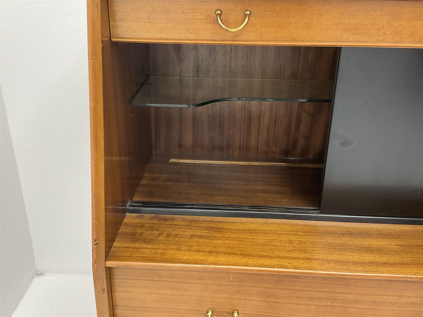 1950s G-Plan retro highboard unit, single long drawer above glazed sliding doors enclosing shaped glazed shelve, alongside a fall front door, above one short and one long drawer, raised on outsplayed tapering supports 