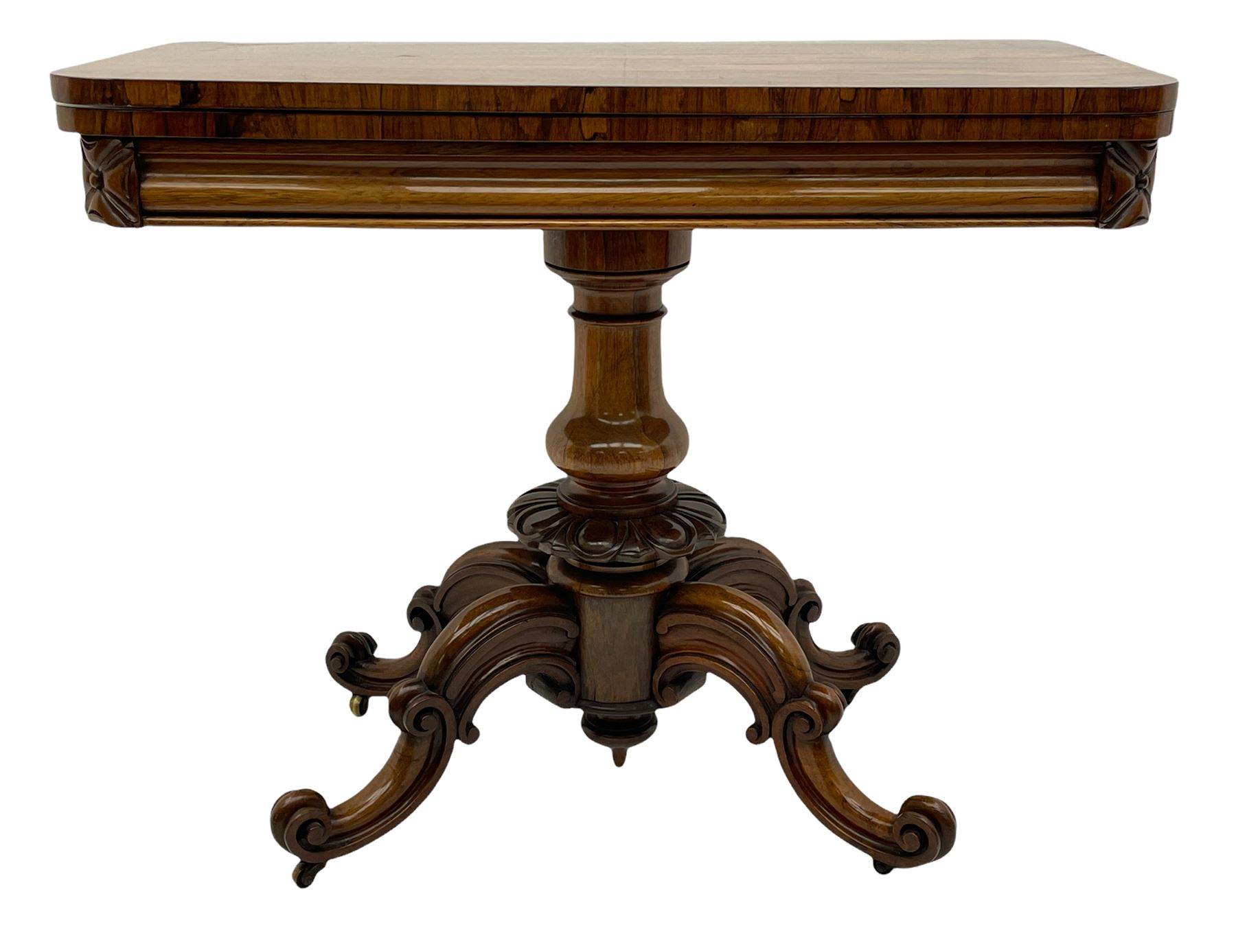 Victorian figured rosewood card table, fold-over swivel top with circular baize lining, moulded frieze with stylised flower head carving to corners, turned column with egg and dart decoration, on quadruple splayed c-scroll carved supports, with brass castors