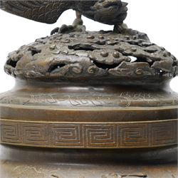 Japanese Meiji period bronze Koro, c.1870-1880, of squat baluster form, each foot with elaborate floral and mythical creature decoration, the body depicting two lions in chase, the rim with Greek key border, the pierced cover with eagle finial, Yoshida foundry mark to base, H50cm