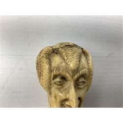 19th century carved ivory walking cane handle, modelled as the head of a greyhound with inset glass eyes, together with a further 19th century ivory example, modelled as a caricature of a gentleman's head, (2)
