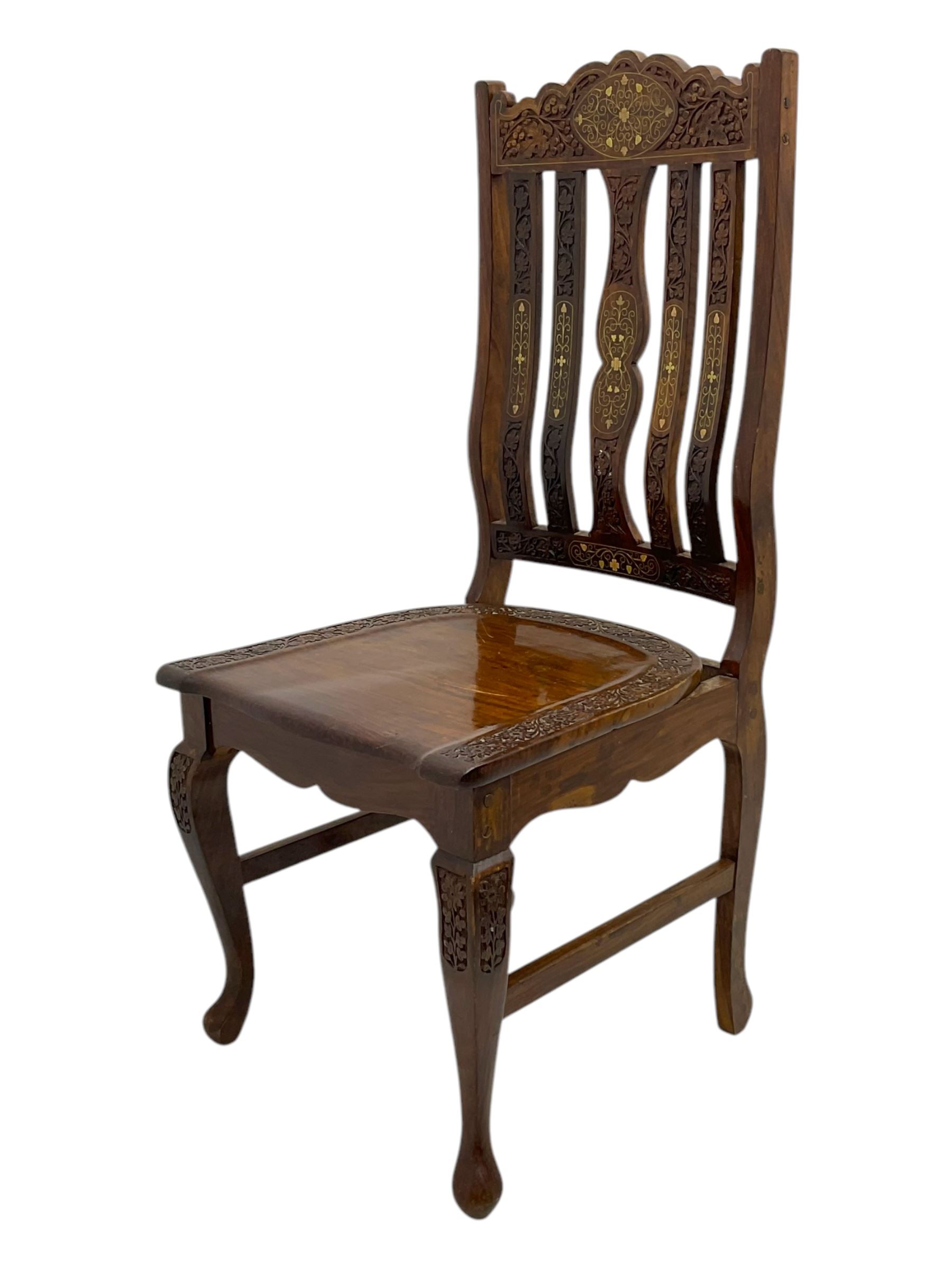 Pakistan carved hardwood brass inlaid circular dining table, and four rail back chairs with saddle seats