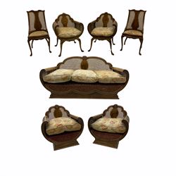 1920's simulated walnut seven piece drawing room bergère lounge suite - three seat settee with curved shell carved cresting rail, the curved arms with leaf carved terminals, shaped plinth base (W167cm), pair tub shaped armchairs with vase shaped splat back, raised on shell carved cabriole supports (W67cm), pair tub shaped armchairs, shell carved cresting rail over vase shaped splat, curved arm supports with leaf carved terminals, shaped plinth base (W81cm), pair side chairs, the shaped cresting rail over vase shaped splat, serpentine seat on shell carved cabriole supports (W46cm)