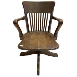 Early 20th century swivel office desk chair, shaped bar back over vertical rails, dished seat, on four splayed supports