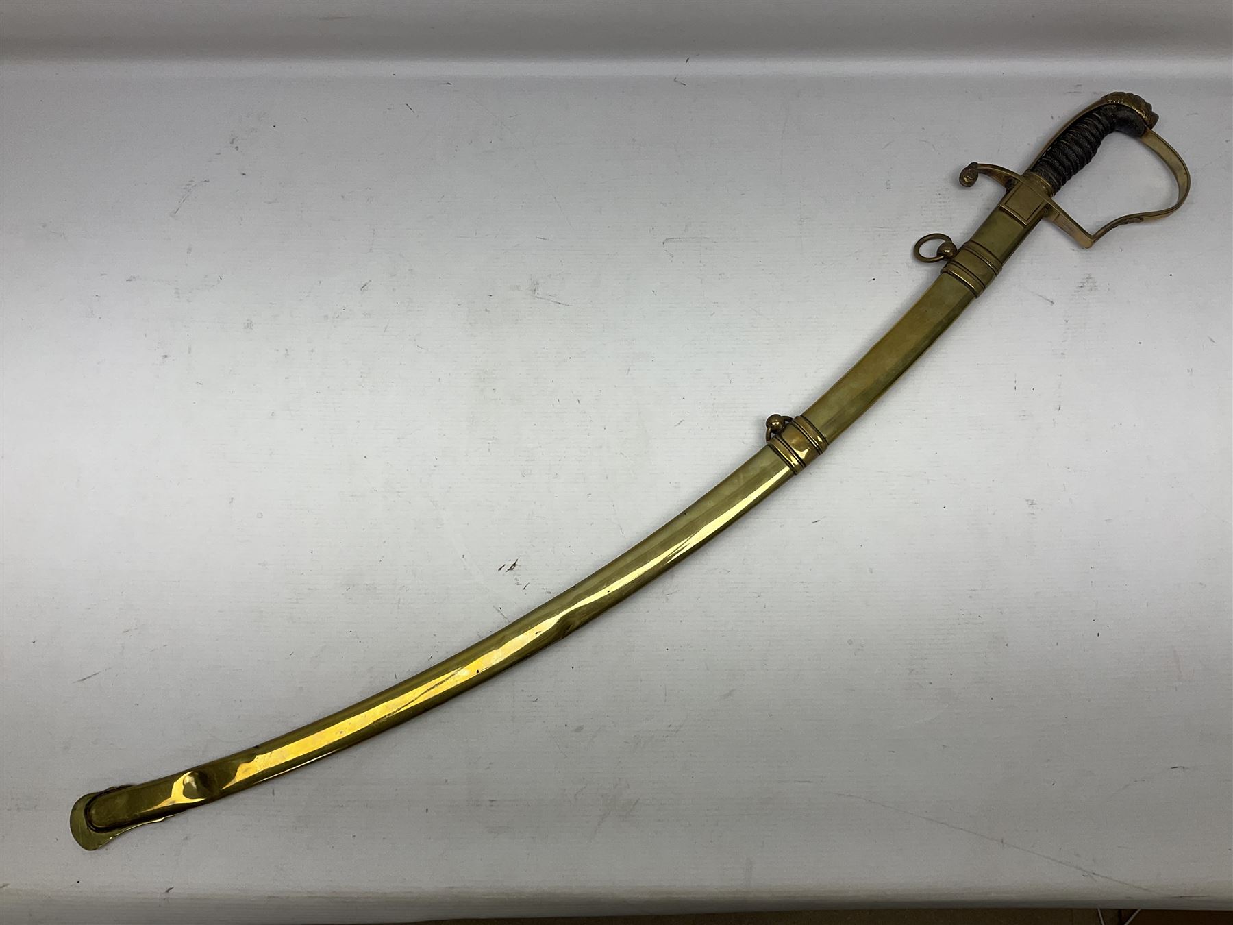 German Saxon 1st Empire Light Cavalry officer's sword c1820s, the 79cm clipped curving blade engraved with the crest of Hanover and various battle trophies with traces of blueing and gilding, brass hilt with knucklebow, foliate square langets, ornate downswept quillon, wire-bound fish skin grip with lion's head pommel; in brass scabbard with two suspension rings L95cm overall