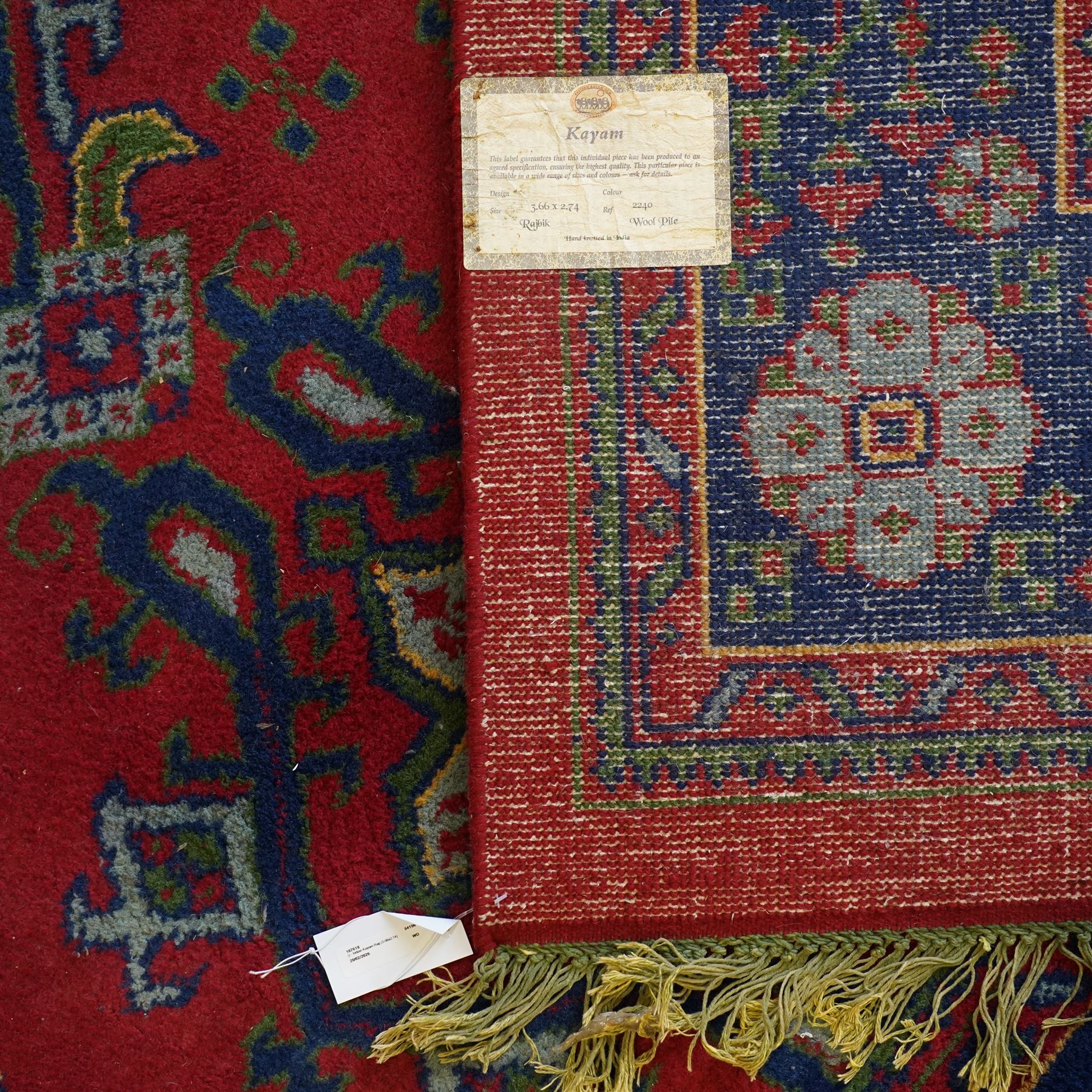 Indian Kayam rug, the rectangular field with repeating geometric medallions on a red ground, within a blue border of stylised floral motifs, with guard borders and fringe terminals