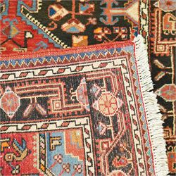 North West Persian Heriz hand-knotted rug, indigo and madder red field with a central angular medallion with stylized floral and geometric motifs within multiple patterned borders with fringe ends 