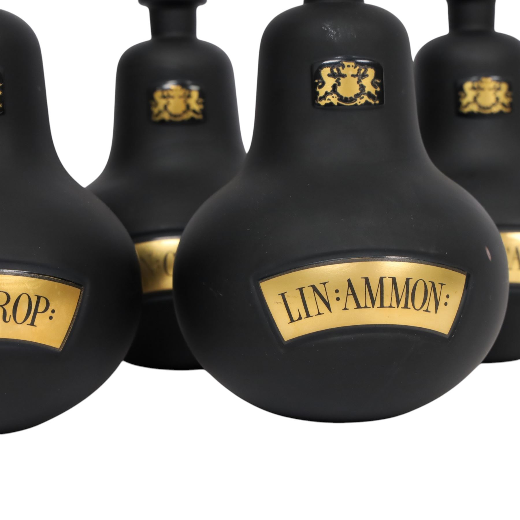 Set of four 20th century Royal Pharmaceutical Society black frosted glass bottles, of bellied form with clear cut glass spire stopper, each body bearing gilt label in Latin: LIN:AMMON:, LIN:ATROP:, LIN:CAMPH:, and LIN:CALCi:, and gilt Royal Pharmaceutical Society crest to neck, H25cm

Provenance: From the collection of the family of Peter Green, a practising pharmacist whose career spanned the mid to late 20th century. During his professional life he managed pharmacies in Yeovil, Somerset, and later Selles Chemist in Filey, North Yorkshire, before purchasing and running his own business, Peter Green Pharmacy, located in the Market Place, Malton. The bottles were displayed as part of the traditional shop fittings in both the Filey and Malton pharmacies and were retained as part of his collection.