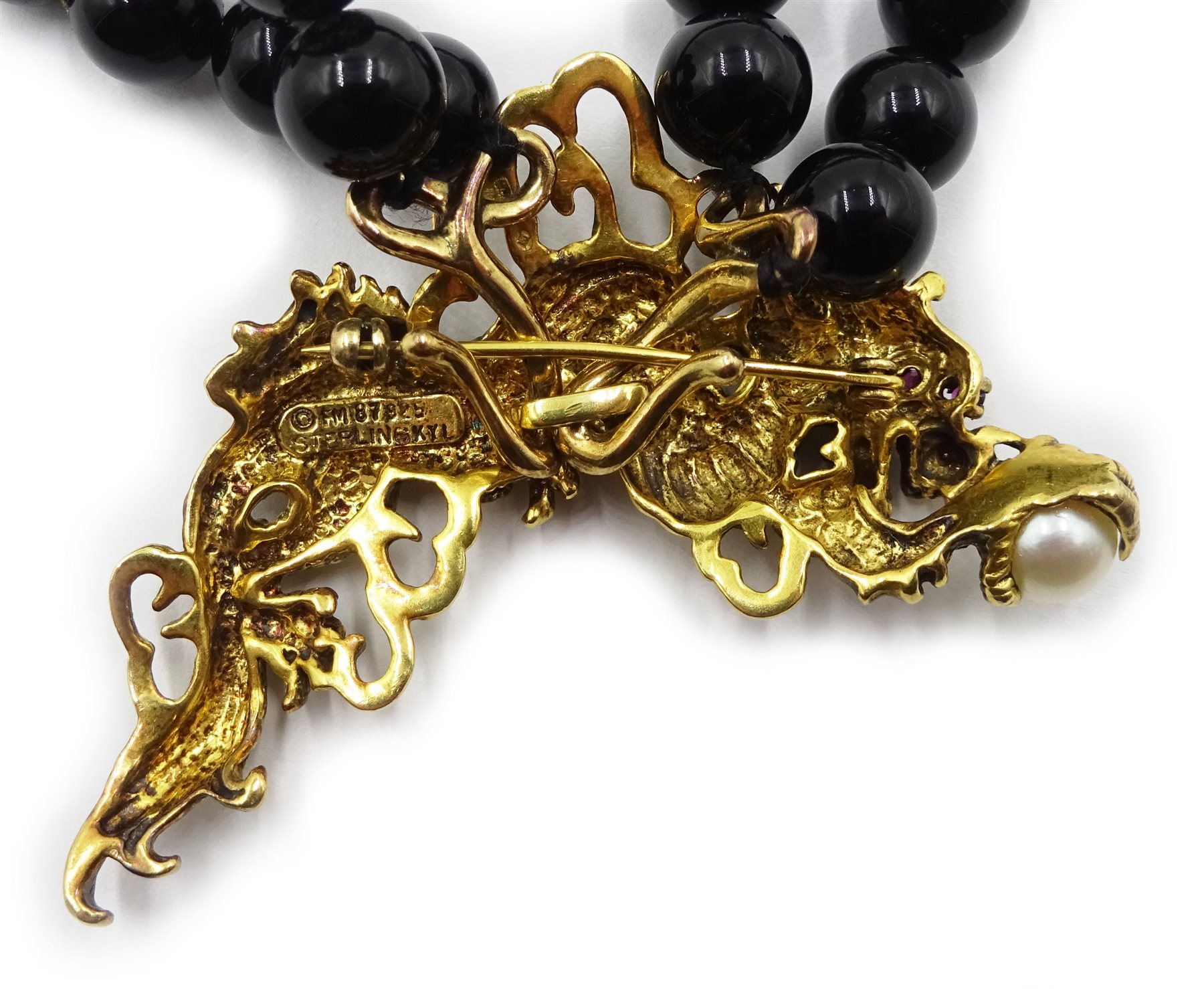 Franklin Mint 'Year of the Dragon' two strand black onyx necklace with detachable silver-gilt brooch set with a pearl and ruby eyes, stamped 925, designed by Kai-Yin Lo ,with certificate