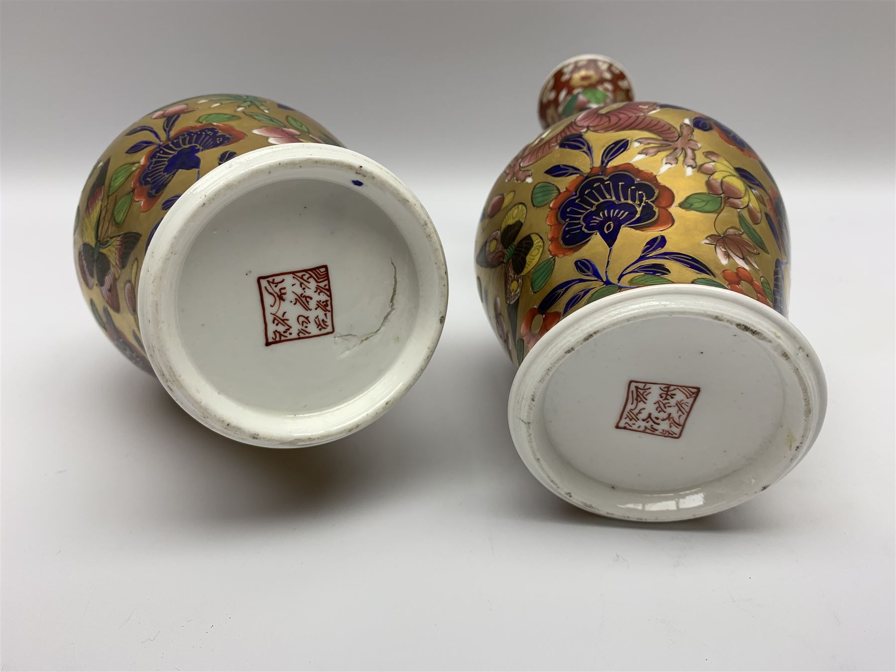 Pair of early 19th century Miles Mason vases, the baluster bodies with tall slender necks supporting twin stylised trunk handles with rings, decorated with Chinese dragons, butterflies, and blossoming flowers against a gilt ground, with spurious Chinese marks beneath in iron red, H27.5cm