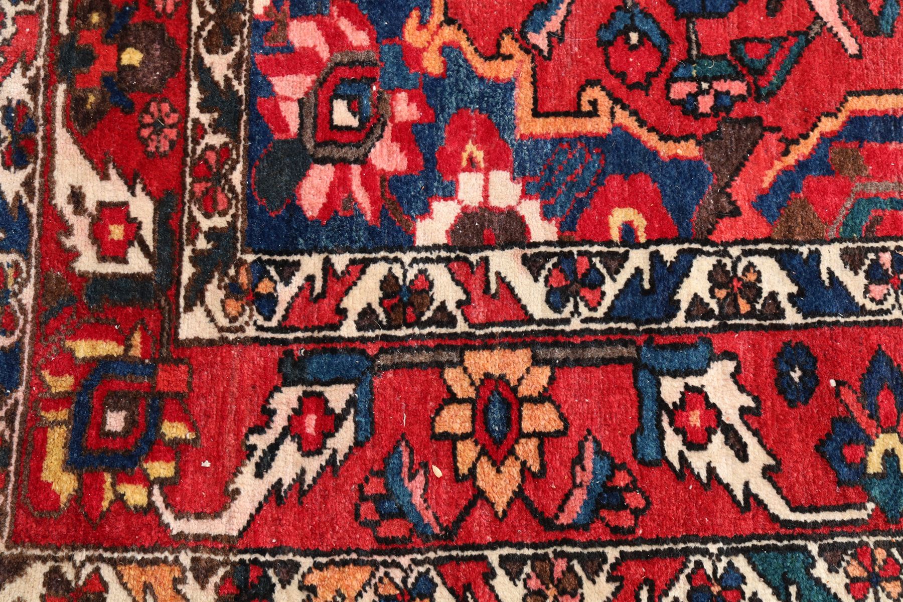 Vintage Persian Heriz crimson ground rug, the field decorated with a central stylised urn and bird of paradise motifs, the guard  lines with repeating stylised plant motifs of geometric form