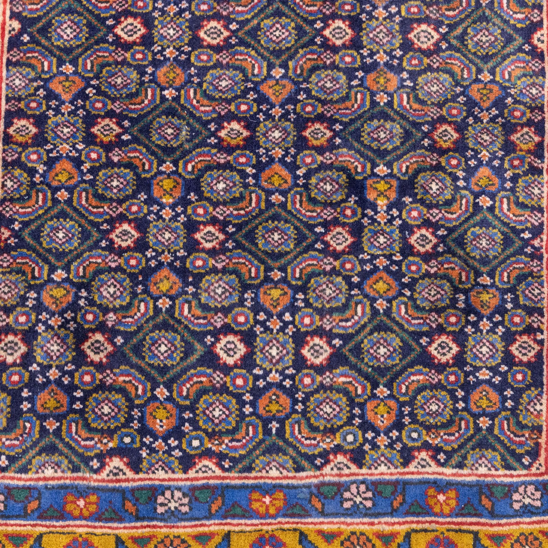 North West Persian Bidjar hand-knotted runner, decorated with an all-over herati pattern on a deep indigo ground, the field is filled with a repeating diamond and rosette motifs, interspersed with stylized leaves and floral elements, framed by a border on an ochre ground flanked by contrasting guard borders, with cotton fringe ends 