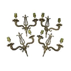 Set of four gilt metal wall sconces, each with lyre backs supporting twin scroll branches 