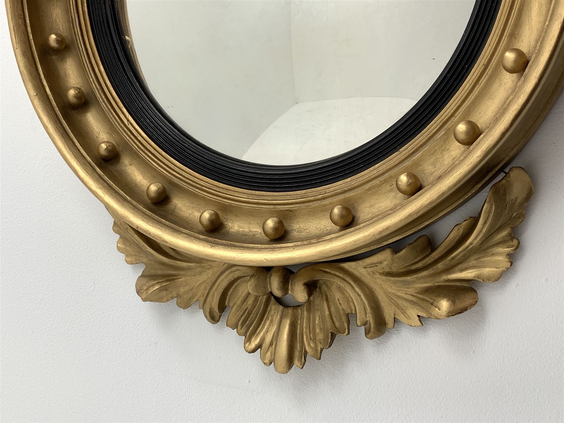 Large Regency carved wood and gesso circular convex mirror, eagle pediment on platform flanked by acanthus leaf scrolls, moulded surround and ebonised slip