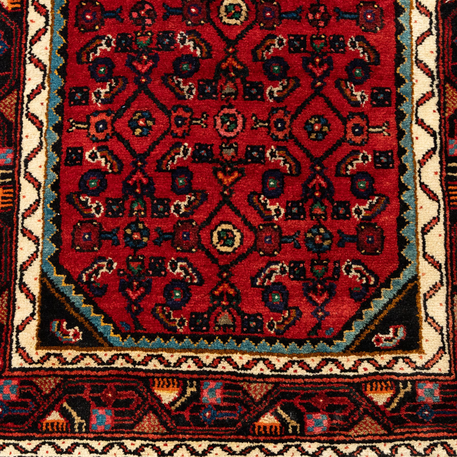 North West Persian Malayer runner, madder red field decorated with an all-over design of stylized herati motifs in shades of indigo, ivory, and green within ivory and dark blue borders of angular vine and rosette design, with cotton fringe ends 