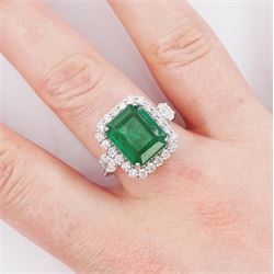 18ct white gold emerald and round brilliant cut diamond cluster ring, with two oval cut diamonds set either side and diamond set shoulders, stamped, emerald approx 4.30 carat,. total diamond weight approx 1.05 carat