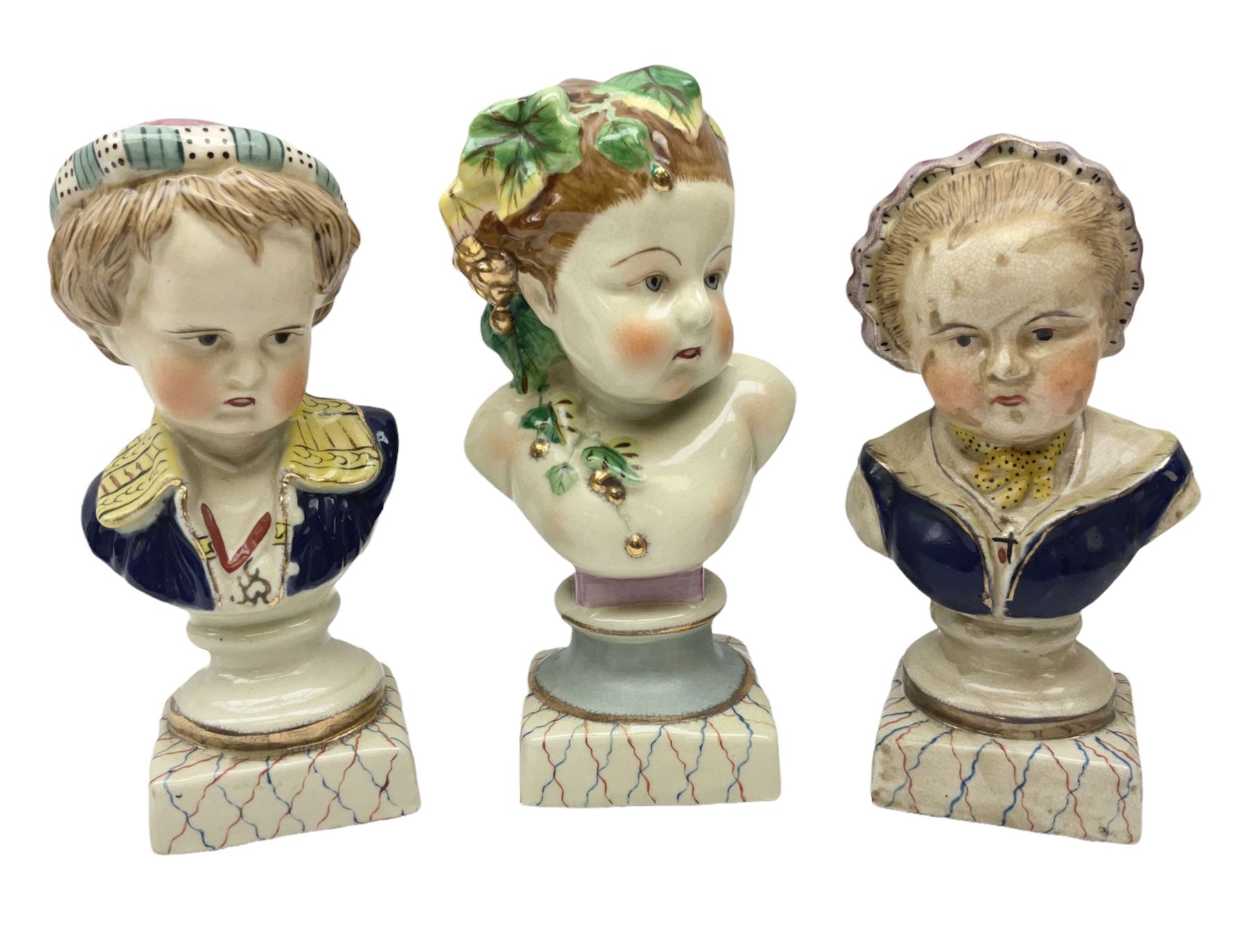 19th century pair of hand painted ceramic busts of children, together with a third similar example of a putti with a crown of ivy, tallest H23cm 