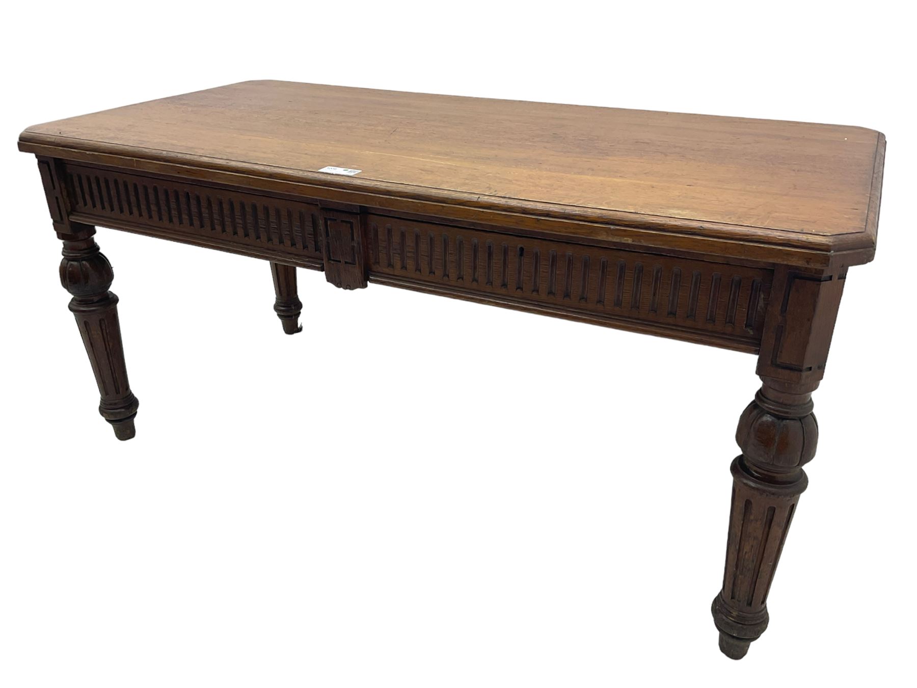 Late 19th century oak library table, moulded rectangular top with canted corners, fitted with two frieze drawers with fluted facias, on lobe carved and fluted turned supports 