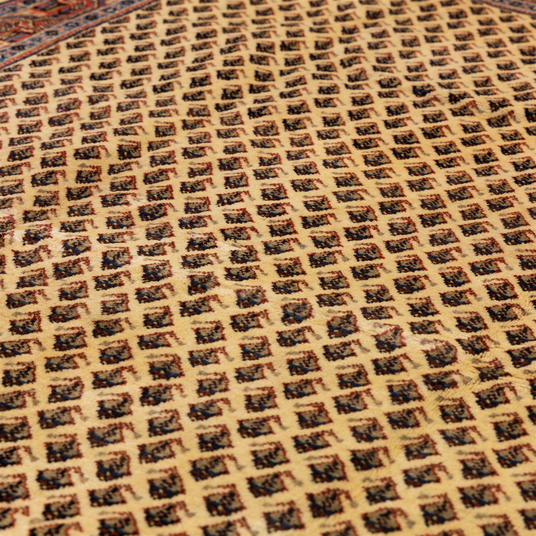 West Persian Boteh-Mir hand-knotted rug, ivory field densely decorated with a repeating lattice of of small boteh motifs arranged in diagonal rows enclosed by a broad border of stylized geometric devices and angular floral ornament between multiple guard stripes with cotton fringe ends 