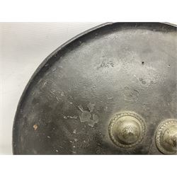 Indian black lacquered hide shield/dhal, of circular convex form with strongly outward-turned brim, fitted at its centre with four metal bosses, each of hemispherical form, with traces of silvered foliate decoration, the bosses corresponding on the inside with four iron rings for enarmes D49cm