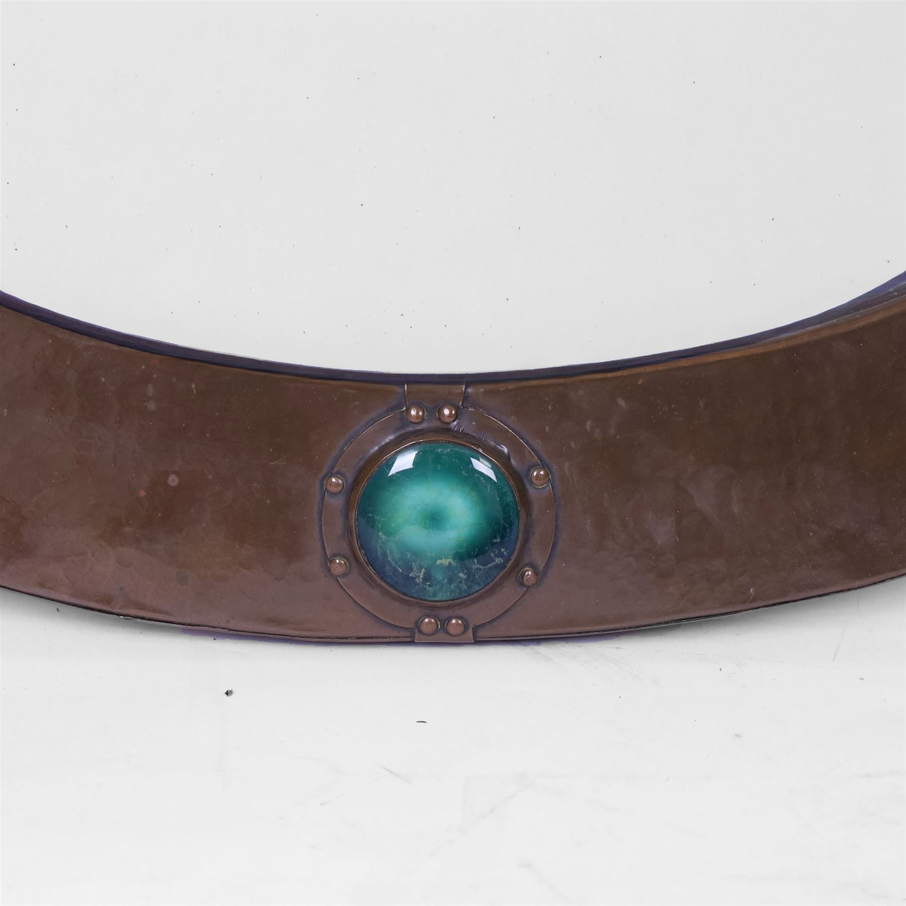 Liberty & Co, Arts and Crafts hammered copper framed oval wall mirror, mounted by four turquoise Ruskin cabochon roundels, with ivorine maker's label verso