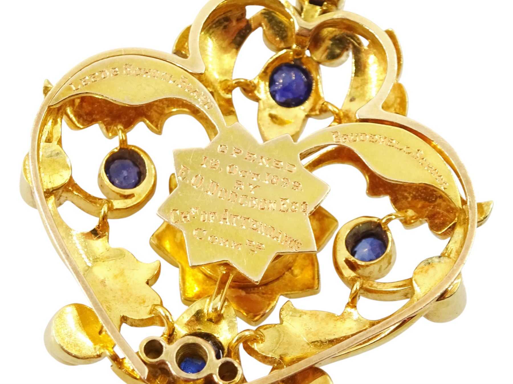 Victorian 15ct gold sapphire and split pearl pendant / brooch, the central flower head cluster set with a round cut sapphire surrounded by pearls, amongst an openwork setting set with four further sapphires and pearls, the reverse with presentation engraving and detachable brooch setting
